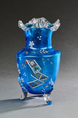un vase en verre bleu posé sur un socle, sur une surface grise