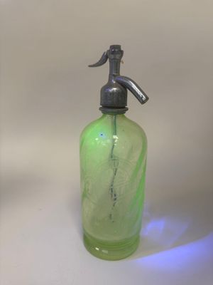 a green glass bottle with a metal spout on it