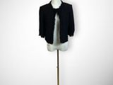 black jacket on a mannequin stand with a pink flower in front of it