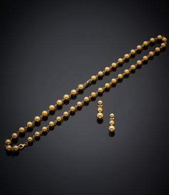 a gold beaded necklace and earrings set on a black background