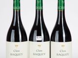 trois bouteilles de vin rouge sont alignées sur une surface blanche