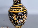 a black and gold vase sitting next to a plate on a table