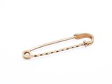 a close up of a gold safety pin on a white background