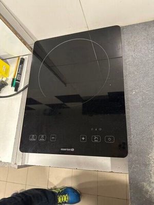 une personne debout devant une cuisinière sur laquelle se trouve un brûleur noir