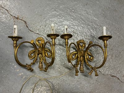 trois appliques murales en laiton vieilli posées sur un sol en béton