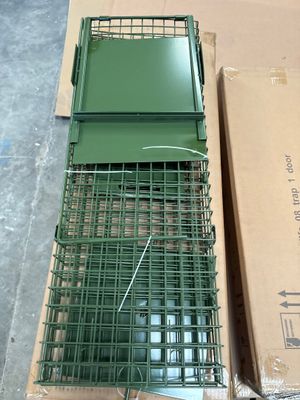 a green cage with a bird inside of it on a box
