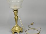 an antique brass table lamp with a glass shade and a cord