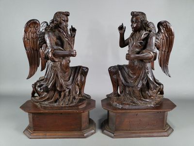 une paire de statues d'anges en bronze assis sur des socles, sur fond blanc