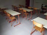 rows of desks and chairs in a classroom with a projector screen in the background