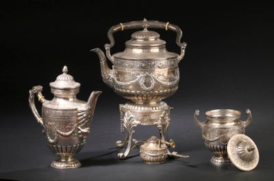 une théière en argent et deux tasses en argent posées sur une table