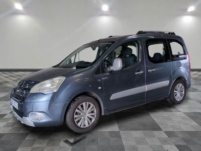 the small blue van is parked on a checkered tile floor