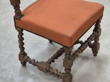 une petite chaise en bois sur laquelle est posé un coussin orange