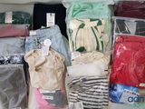 de nombreux types de vêtements différents, rangés dans des sacs posés sur la table
