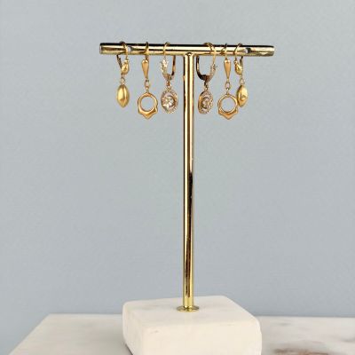a gold plated jewelry stand with five pairs of earrings hanging from it