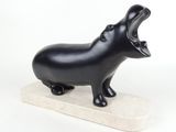 sculpture représentant un hippopotame à la gueule ouverte, posée sur un socle en marbre