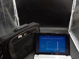 un ordinateur portable posé sur une table, avec un sac à côté