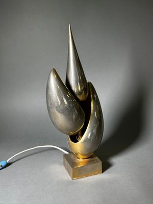 une sculpture en argent et en or posée sur un socle en bois