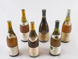 six bottles of wine are lined up in a row on a white surface