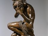bronze statue of a man sitting on a pedestal with his hand on his chin