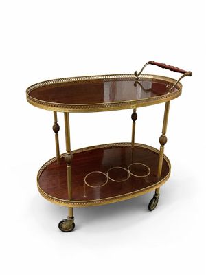 un chariot de bar en laiton et en verre, muni de deux étagères et monté sur roulettes