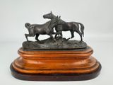une statue en bronze représentant deux chevaux, posée sur un socle en bois