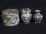 three silver vases sitting next to each other on a black background