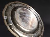 a silver plate sitting on a stand on a black surface