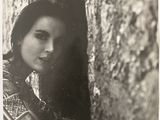 une vieille photo en noir et blanc d'une femme adossée à un arbre