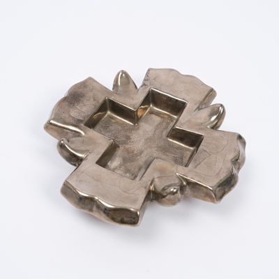 croix plaquée argent sur une surface blanche, sur fond blanc
