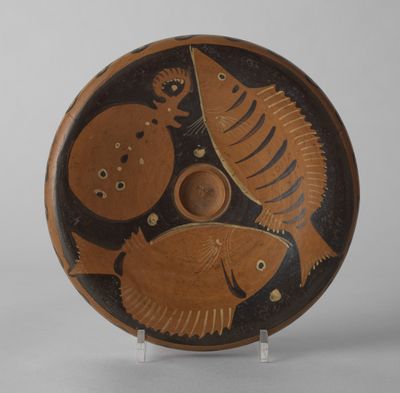 une assiette marron et noire ornée d'un motif de poisson