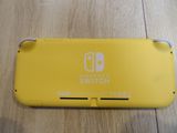 a close up of a nintendo switch lite sitting on a wooden floor
