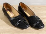 black loafer shoes on wooden surface with white wall in background