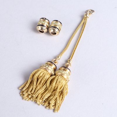 une paire de pompons dorés et une paire de boucles d'oreilles posés sur une surface blanche