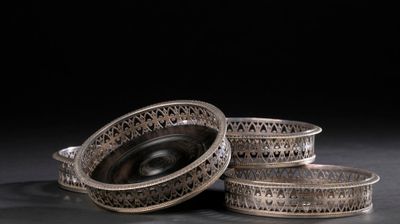 trois plats en argent posés sur une surface noire, avec un fond noir