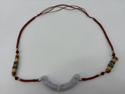 une photo d'un collier composé de perles de verre et d'un fil rouge