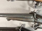 several old guns are lined up on a white surface