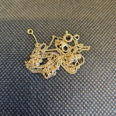 un tas de chaînes en or posées sur une surface noire