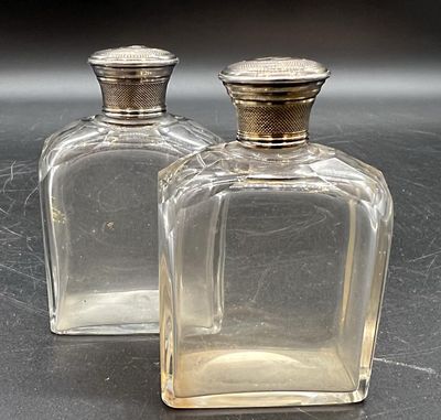 deux bouteilles en verre transparent avec des bouchons argentés posées sur une table