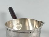 a small metal bowl with a wooden handle on a white surface