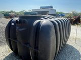 a large black tank sitting on a gravel lot