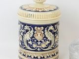 a blue and white jar with a lid next to a rock