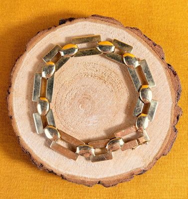 a wooden slice with a bracelet on it on a yellow background