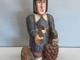 figurine en bois représentant un homme coiffé d'un chapeau et tenant une grappe de raisin