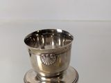 an antique silver plated cup on a stand on a white surface