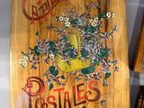 a wooden sign with a basket of flowers on it
