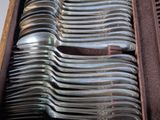 a lot of silver spoons in a wooden box
