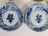 four blue and white plates with chinese characters on them