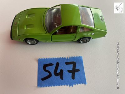 une petite voiture verte posée à côté d'une feuille de papier bleue