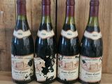 quatre bouteilles de vin sont alignées sur une étagère en bois