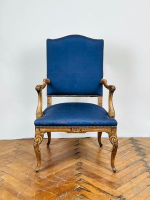 une chaise bleue posée sur un parquet, près d'un mur blanc